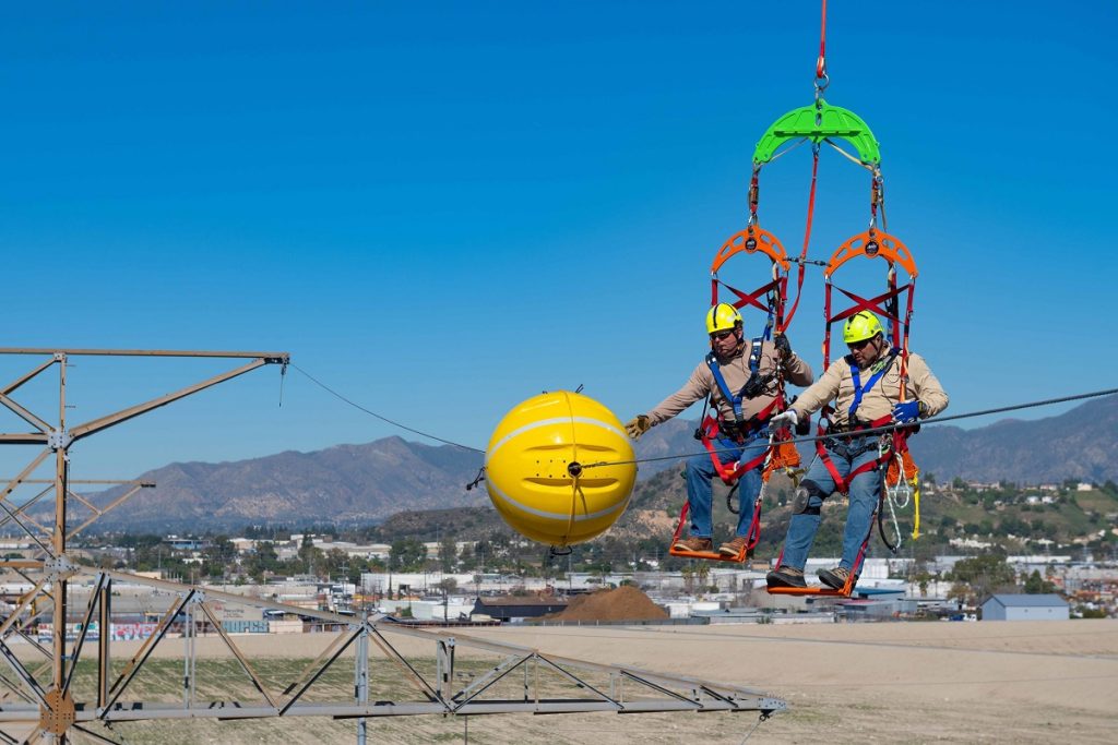 Installatie van een bol op een hoogspanningsleiding.