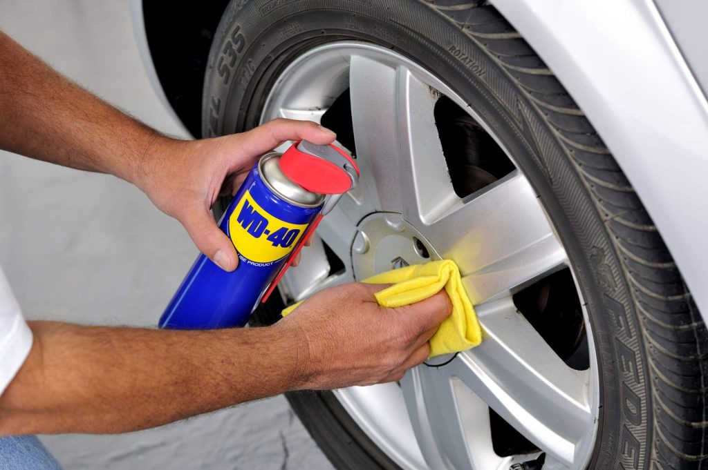 De man gebruikt deze spray om kras van zijn auto te verwijderen.